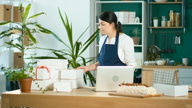 Una piccola imprenditrice di successo prepara l'ordine di un cliente cucina moderna di design