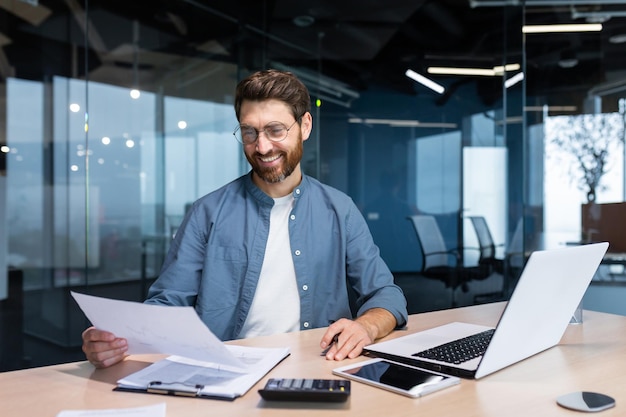 Successful financier investor works with documents and accounts inside office businessman with beard