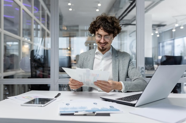 Successful financier investor works with documents and accounts inside office businessman with beard