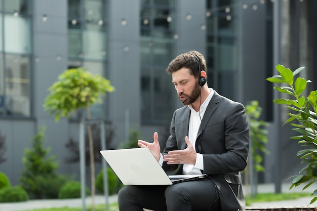 Successful freelancer man conducts online consultation uses a headset with a microphone and a laptop for video communication