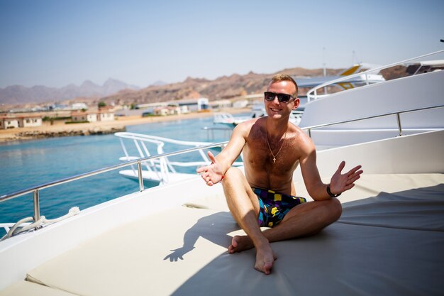 Successful guy sit on a white yacht with sea view. Red sea, bright sun