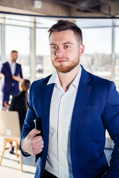 Successful handsome male mentor, director, businessman in a suit at the office. Working day concept. Team meeting with the boss in the foreground