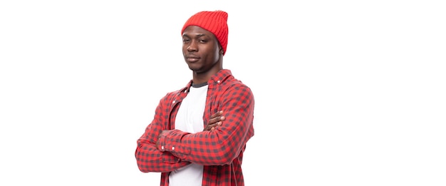 Successful handsome s black american man dressed in red shirt and cap on white studio background