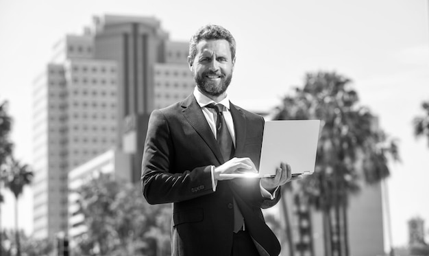 Successful happy businessman in suit working on laptop standing outdoor office worker