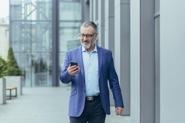 Successful and happy senior grayhaired businessman investor\
walking outside office building man