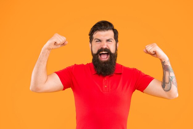 Photo successful hipster male with beard on yellow background success