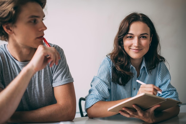 successful intelligent woman with paper textbook in hands smiling at camera during brainstorming