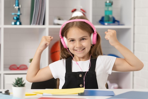 Successful kid listen to music in headphones at school classroom