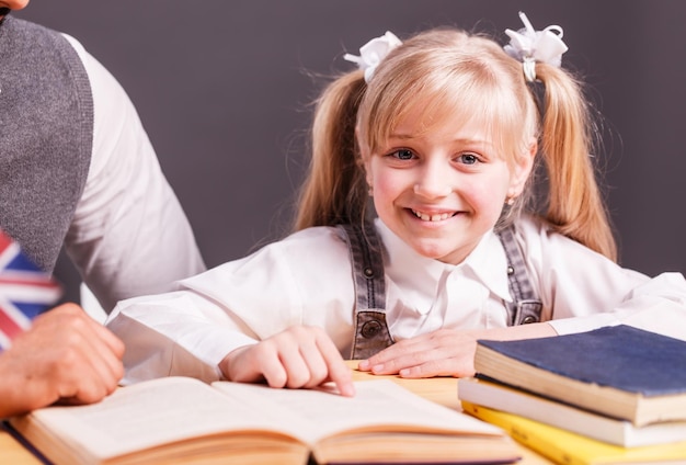 Successful kid student girl smile while reading English book with teacher help