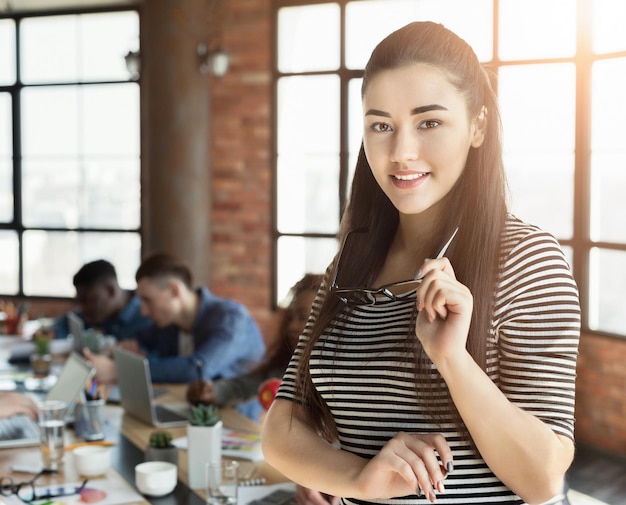 Successful lady boss smiling at camera, posing at loft office, copy space