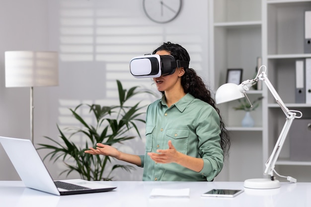 Successful latin american woman in office using vr glasses for video call and chatting online in