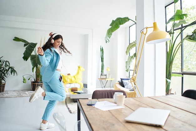 Successful latina businesswoman dances in office dress celebrating happily at work