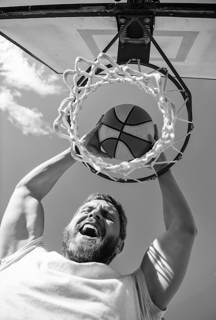 Il giocatore di successo dell'uomo lancia la palla da basket attraverso il successo del cestino