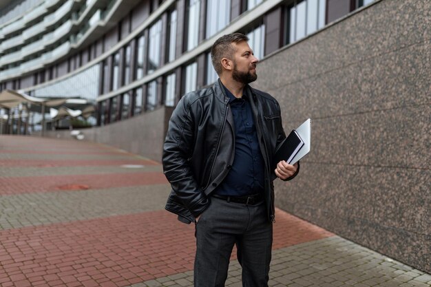 Photo successful man with documents of an architect on the background of a dark building