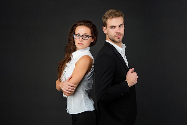 Successful man and woman in business look on black background, partners.