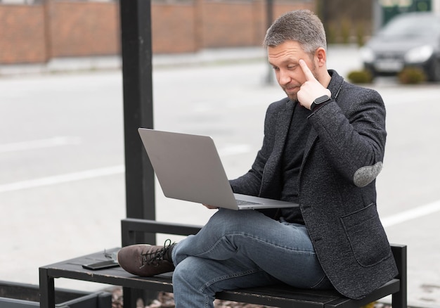 Успешный мужчина работает на улице с ноутбуком
