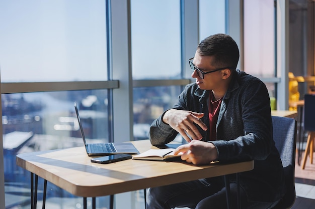 Manager di successo che lavora con il rapporto di investimento delle informazioni aziendali del caffè scrivendo note mentre si fa ricerche online sul marketing digitale dei computer portatili lavoro fuori dall'ufficio