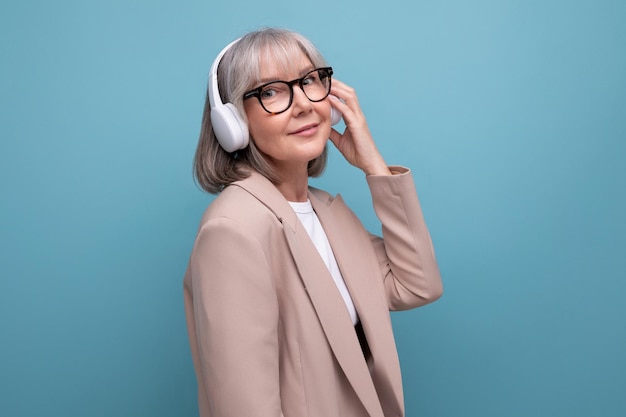 Successful mature business lady with wireless headphones enjoying music on bright background with