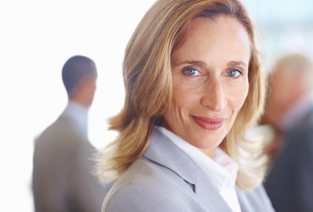 Successful mature business woman with executives Closeup of successful mature business woman looking at you with executives in background