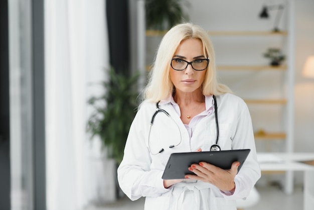 Successful mature caucasian senior female doctor in white coat at hospital