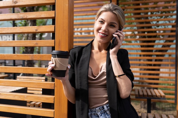 Donna di mezza età di successo che parla al telefono durante una pausa pranzo in un bar