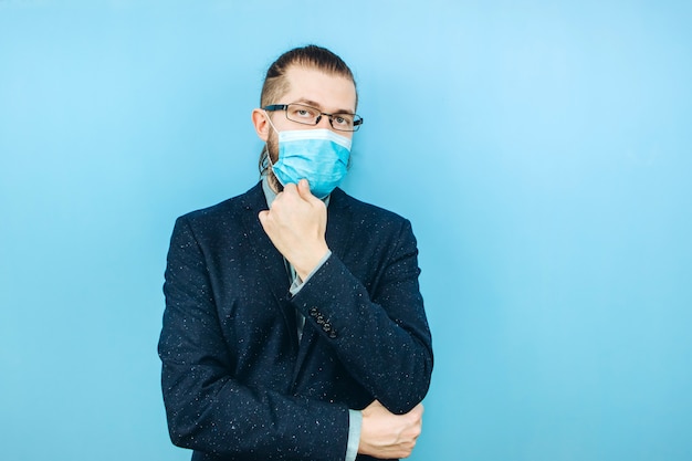 A successful muschin in a suit, glasses and a medical mask on a blue