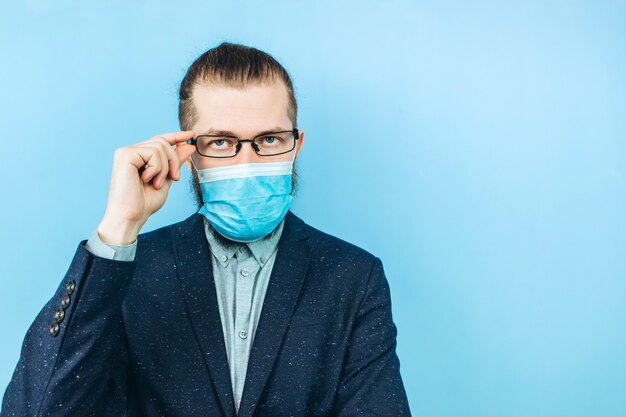 A successful muschin in a suit, glasses and a medical mask on a blue