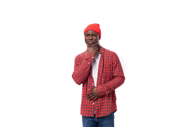 Successful pensive s black american man dressed in red shirt and cap on white studio background with