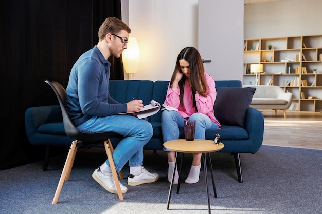 Successful psychotherapy Woman having session with psychologist sitting on couch at clinic The woman is very upset the psychotherapist is trying to help her with the problem