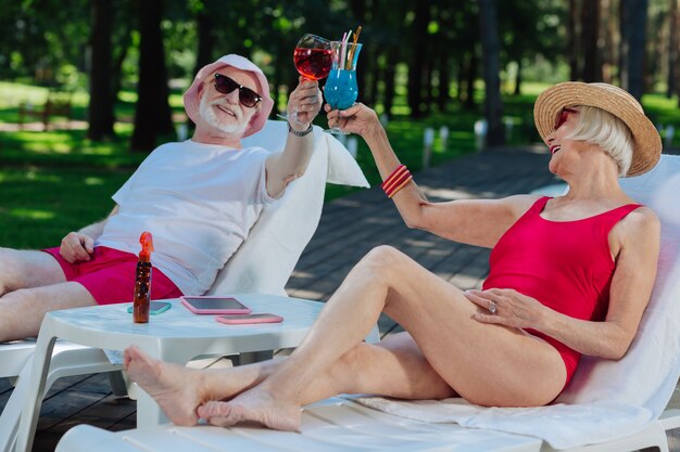 Successful retired man and woman feeling relaxed while chilling near outside pool