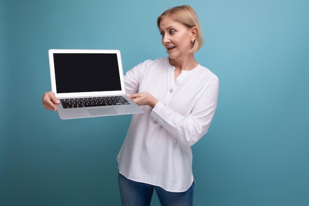 Successful s middle aged woman with blond hair demonstrates a laptop with mocup