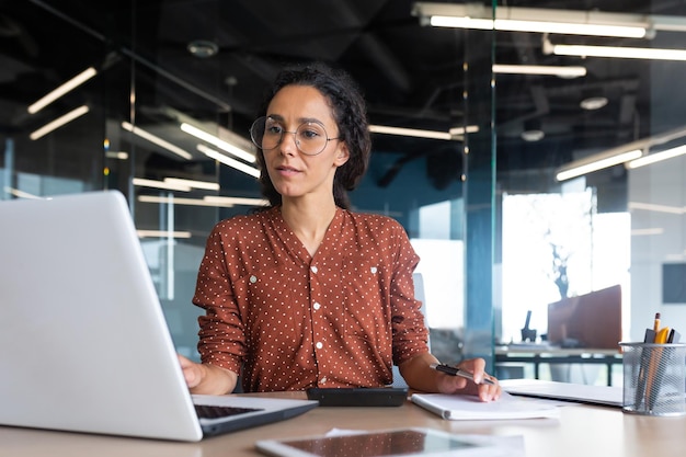 Successful satisfied and happy business woman working inside\
modern office hispanic woman in glasses