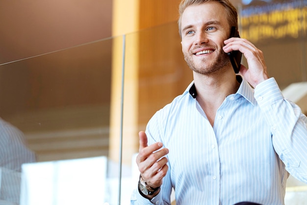 Successful smart caucasian businessman walking on stair make communication with smartphone communicate with happiness and enthusiastic modern office background