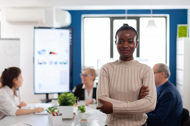 Successful smiling african business woman holding arms crossed looking atcamera in conference room