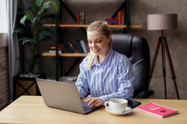 Successful smiling young businesswoman using laptop and computer at the office