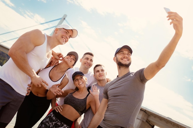 successful sports team taking selfie afther workout on the beach.
