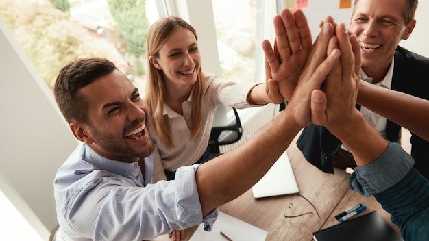 Successful team business people giving each other highfive and smiling while working together in the