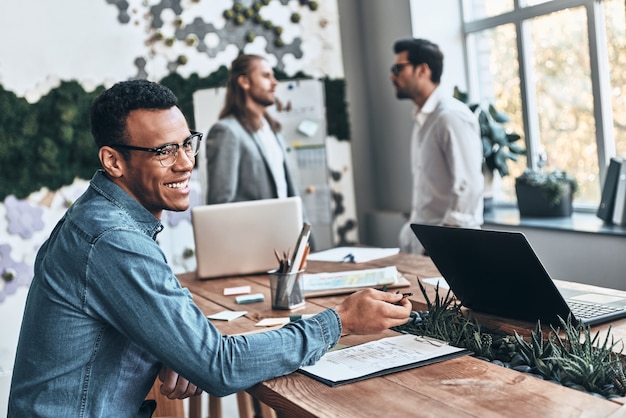 Foto squadra di successo. gruppo di giovani moderni in abbigliamento casual intelligente che discutono di affari mentre lavorano nell'ufficio creativo