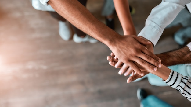 Photo successful team top view of business people holding hands together while standing in the office