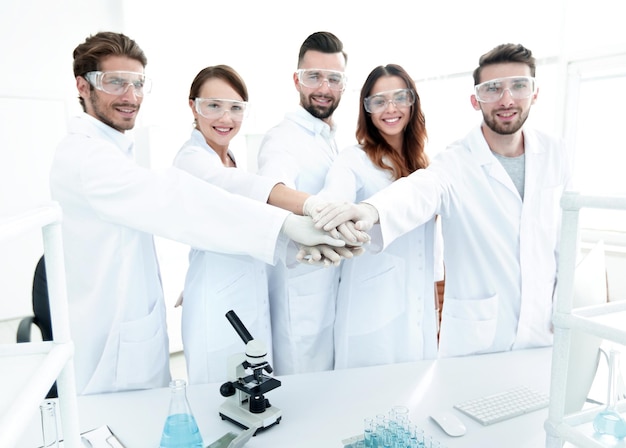 Foto team di successo di giovani scienziati con le mani giunte insieme