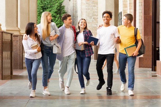 成功したテストの学生が大学キャンパスで歩いて外でチャットしている