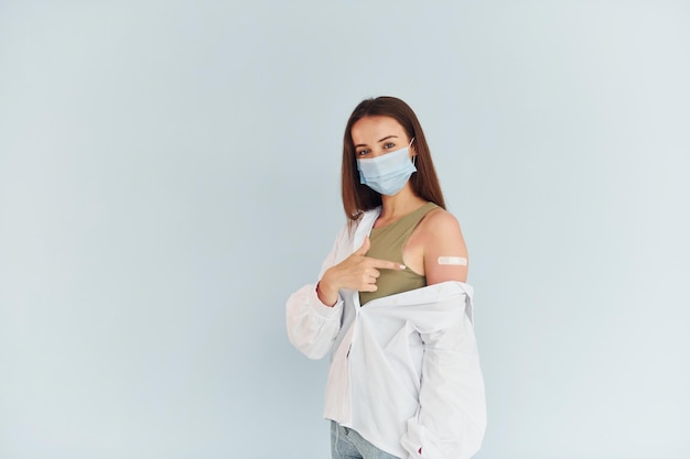 Successful vaccination Young woman in white clothes sitting indoors against white background