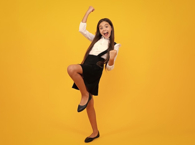 Successful winner child Excited expression cheerful and glad Child with positive expression joyful and exciting over yellow background with empty space Happy teenager girl rejoices success