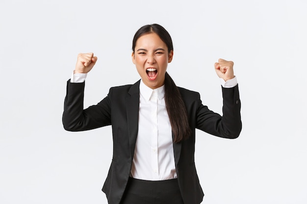 Successo vincente pompa pugno donna d'affari e gridando sì dalla felicità e felice, raggiungere l'obiettivo, celebrare la vittoria, trionfare sul premio, in piedi sfondo bianco