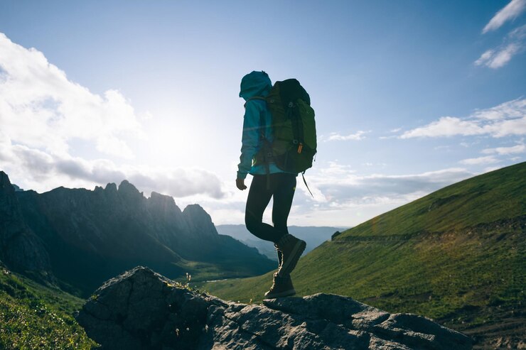 Photo successful woman backpacker hiking on sunset alpine mountain peak