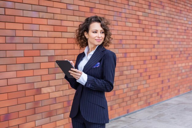 Foto donna di successo vestita in un vestito elegante che posa davanti all'ufficio donna leader aziendale