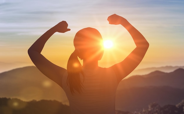 Photo successful woman has achieving new peak of personal growth and development woman on mountain peak with hands up welcoming new day with sunrise female leader winner on top