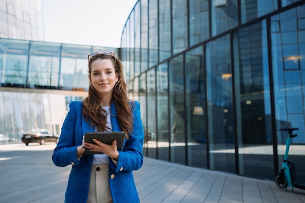 Successful woman real estate agent holding tablet and looking to camera business centre location hig