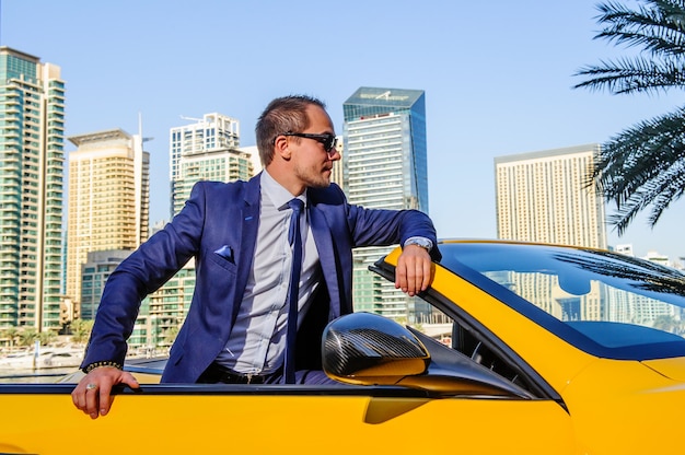 Successful yang businessman in yellow cabrio car.