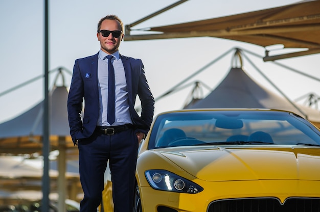 Successful yang businessman in yellow cabrio car.